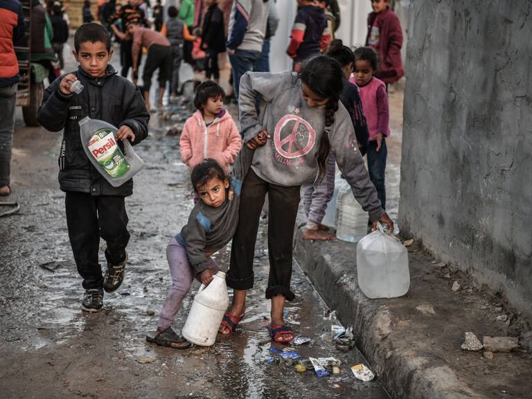 Un grupo de niños palestinos llevan envases con agua, en medio de la guerra que lleva adelante Israel contra la Franja de Gaza en Palestina.