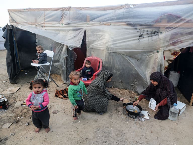 Dos mujeres palestinas preparan algo de alimento para darles de comer a cuatro niños en la Franja de Gaza en Palestina.