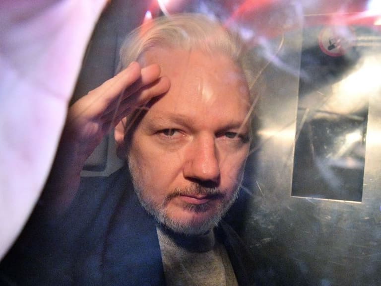 WikiLeaks founder Julian Assange gestures from the window of a prison van as he is driven out of Southwark Crown Court in London on May 1, 2019, after having been sentenced to 50 weeks in prison for breaching his bail conditions in 2012. - A British judge on Wednesday sentenced WikiLeaks founder Julian Assange to 50 weeks in prison for breaching his bail conditions in 2012. Assange took refuge in Ecuador&#039;s London embassy to avoid extradition to Sweden and was only arrested last month after Ecuador withdrew his asylum status. (Photo by Daniel LEAL / AFP) (Photo by DANIEL LEAL/AFP via Getty Images)