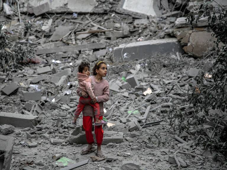 Dos niñas palestinas avanzan entre los escombros que dejan los ataques aéreos de Israel contra la Franja de Gaza en Palestina.