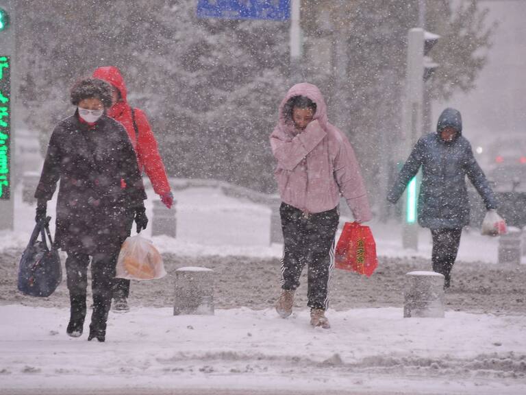 Personas caminan en medio de una gran nevada al noreste de China