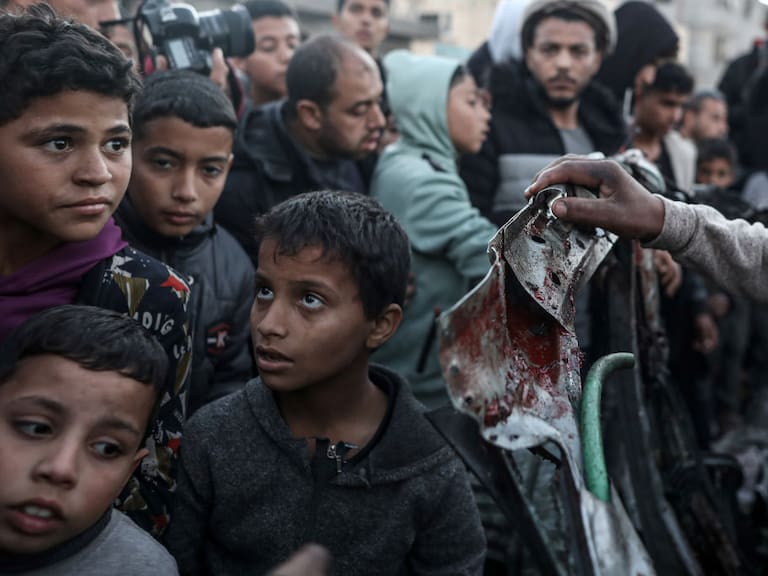 Niños, mujeres y hombres palestinos observan la destrucción que dejan los ataques de Israel en la zona de Rafah en la Franja de Gaza de Palestina.
