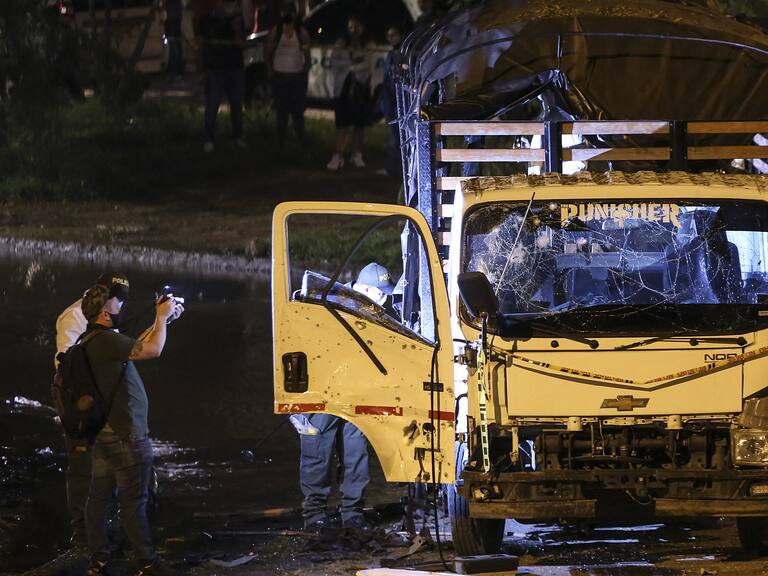 Security personnel inspect a national police truck destroyed by an explosive device in Cali, Colombia on January 8, 2022. - The explosion injured ten police officers and no deaths have been reported yet. (Photo by Paola MAFLA / AFP) (Photo by PAOLA MAFLA/AFP via Getty Images)