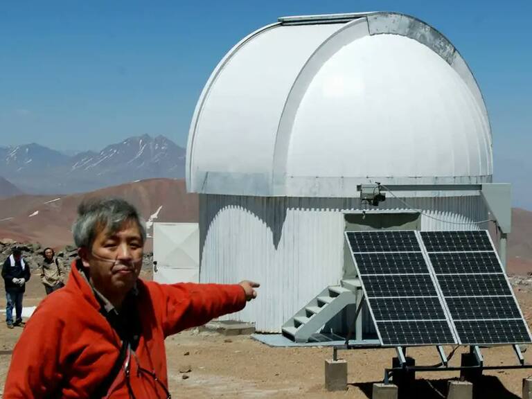 El profesor Takashi Miyata, quien lleva un dispositivo de oxígeno para enfrentar la altitud, señalando el Observatorio de Atacama (TAO) | Foto de Deutsche Welle (DW)
