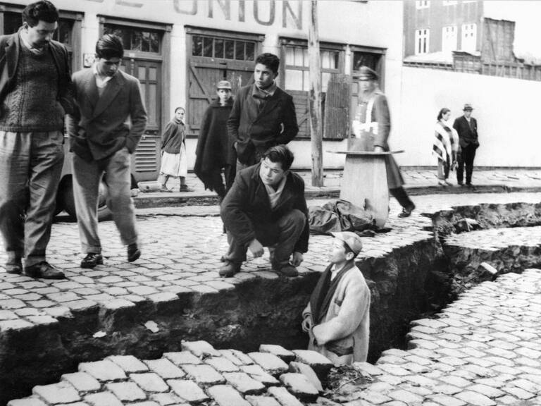 picture taken in April 1960 in Valdivia of people looking at an enormous crack on a street due to the earthquake that struck the area on May 22, 1960.  AFP PHOTO (Photo credit should read STF/AFP via Getty Images)
